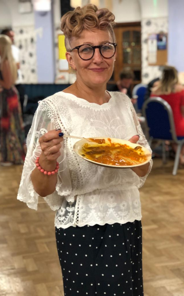 Smiling wedding guest holding a plate of curry catered by Jaflong Tandoori
