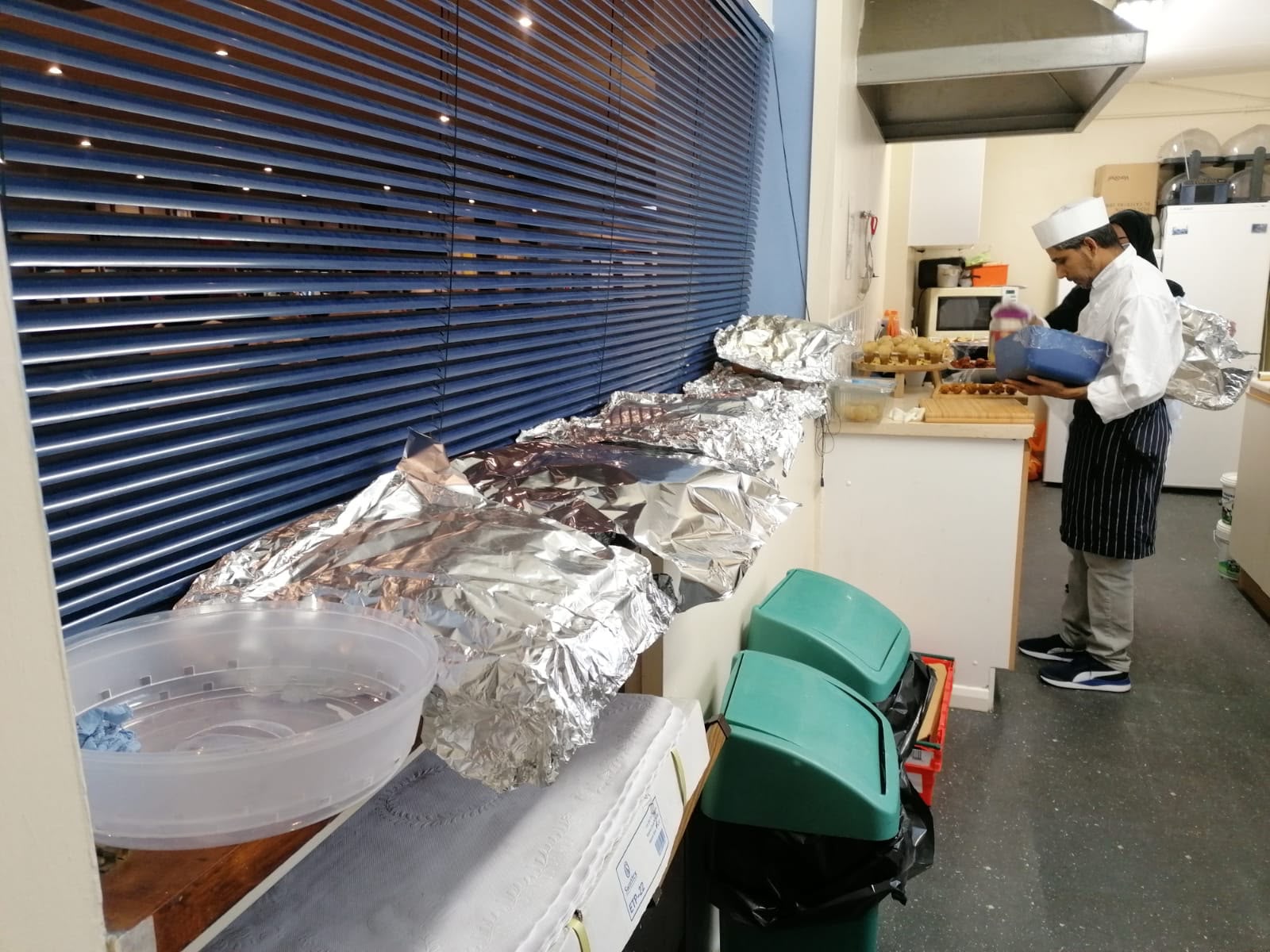 Jaflong Tandoori chef preparing foil-covered catering trays in the restaurant kitchen