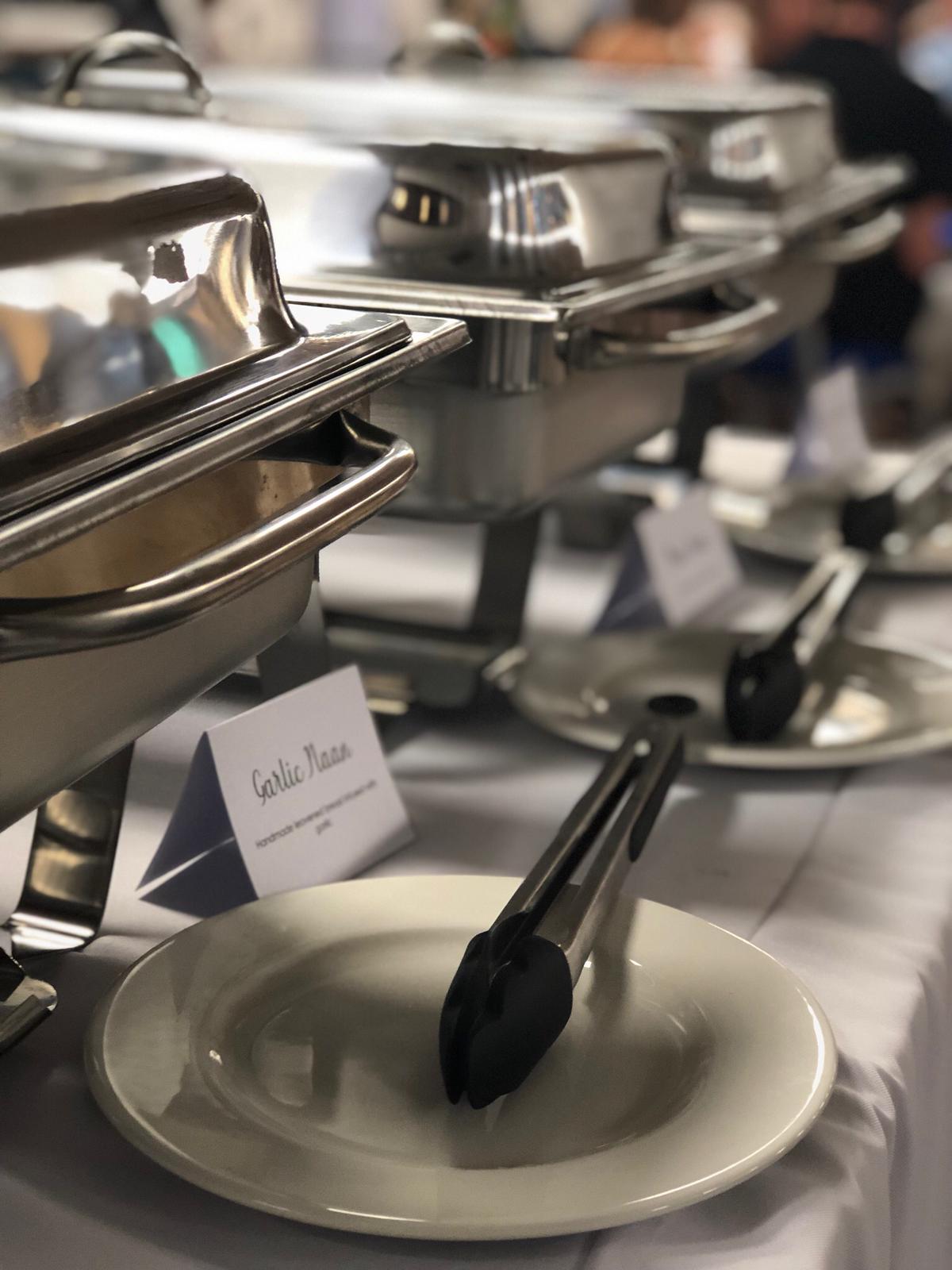 Garlic naan station with serving tongs and place cards at a catered wedding buffet