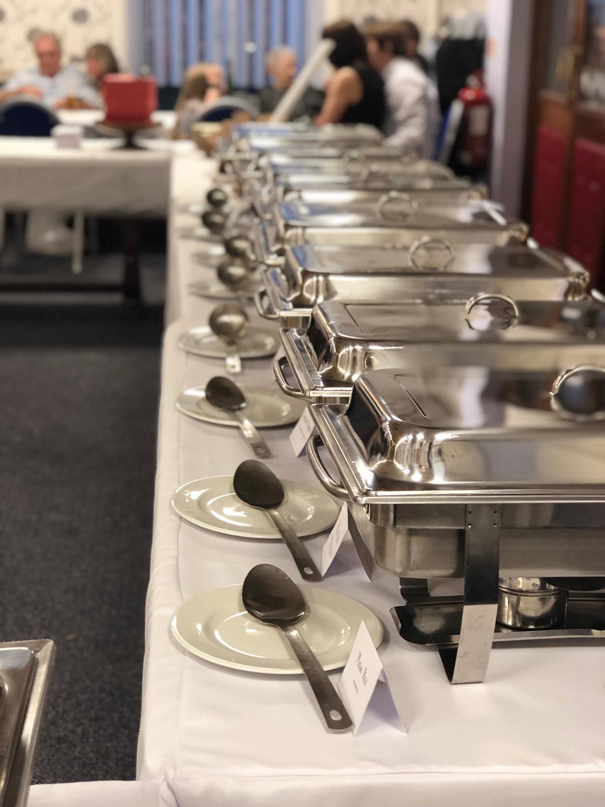 Long line of polished chafing dishes set up for a wedding buffet by Jaflong Tandoori