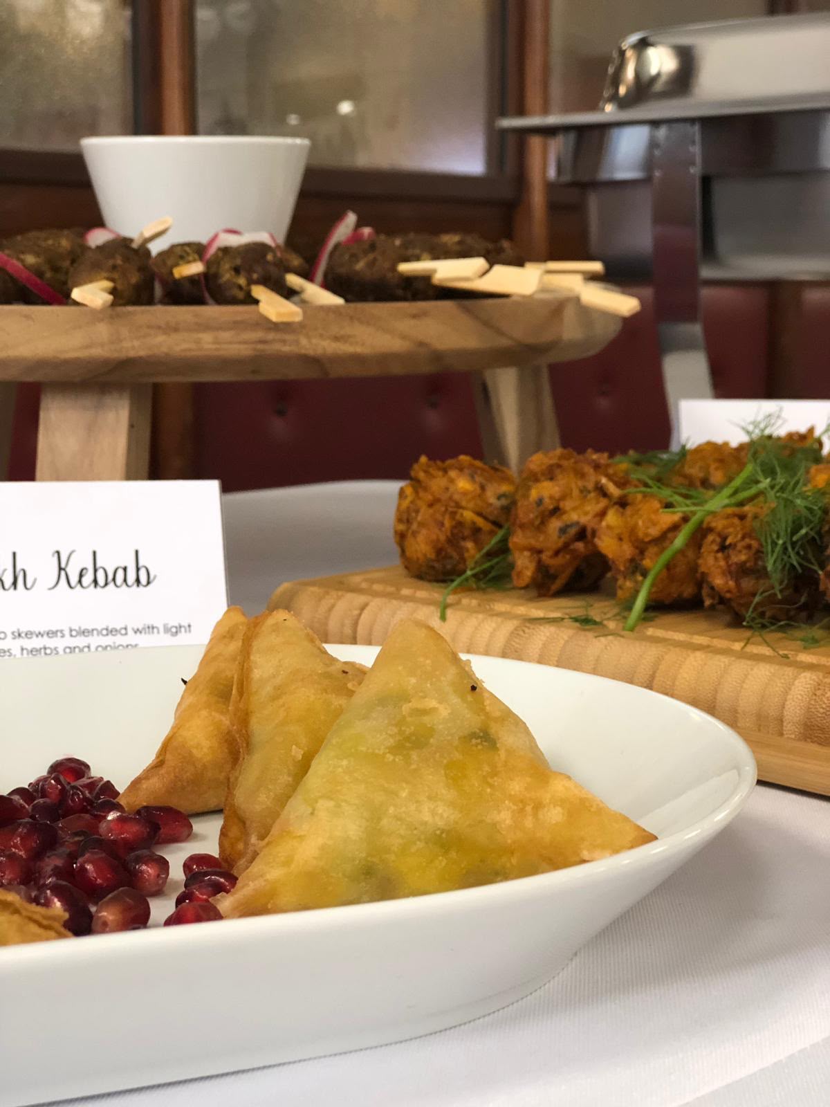 Close-up of freshly fried samosas and pomegranate seeds on a white serving platter